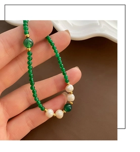 Close-up of green agate beads and white pearls on a handcrafted necklace detail