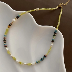 Handcrafted pearl and volcanic stone necklace with peridot accents on a wave tray