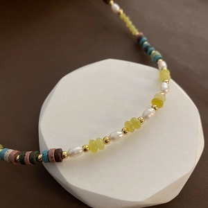 Peridot volcanic stone and pearl necklace displayed on white geometric stand