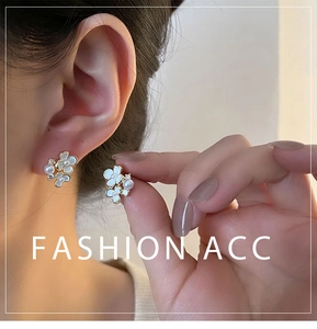 Détail d'une boucle d'oreille fleur blanche avec centre perle et finition dorée