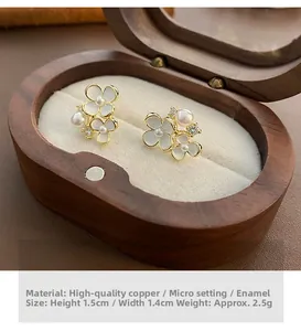 Détail de boucles d'oreilles fleurs blanches avec perles et cristaux sur boîte en velours
