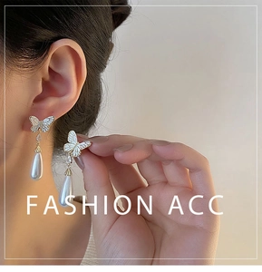 Detail of elegant butterfly earrings with pear-shaped pearls and gold plating