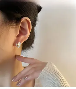 Gros plan d'une boucle d'oreille fleur blanche avec perle portée par un mannequin