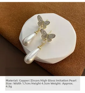 Detail of elegant gold butterfly earrings with teardrop zircon and white pearls