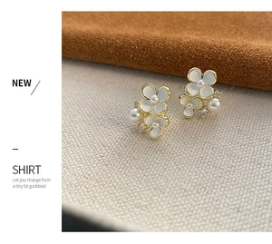 Détail de boucles d'oreilles fleurs avec pétales en résine, perles et cristaux dorés