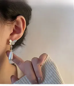 Close-up of elegant butterfly drop earrings with teardrop pearl on female model