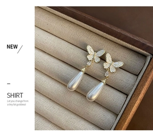 Detailed shot of elegant French butterfly earrings with drop pearl in a jewelry box
