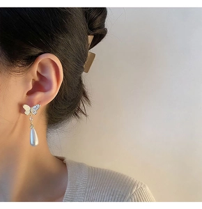 Close-up of French elegant butterfly earrings with long water drop pearl pendants on model