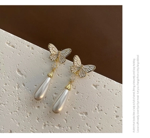 Detailed close-up of French style enamel butterfly earrings with water-drop pearl drops