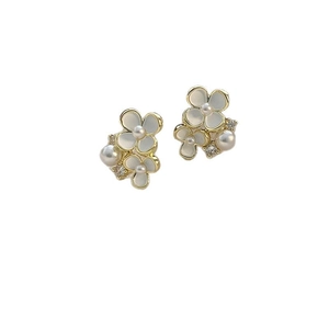 Boucles d'oreilles fleurs dorées avec pétales blancs, perles et cristaux sur fond blanc