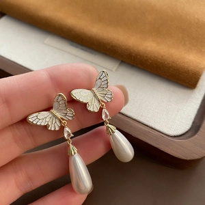 Elegant gold butterfly drop earrings with white pearls and sparkling crystal details