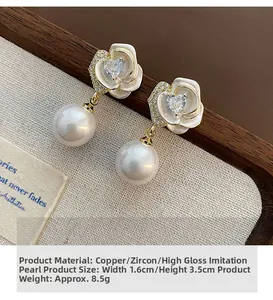 Dettaglio di orecchini a rosa con cuore in zircone e perle a goccia in oro