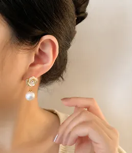 Dettaglio di orecchini a rosa con petali in zircone e una perla su una modella