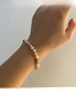 Détail d'un bracelet en perles d'eau douce multicolores porté au poignet sous le soleil