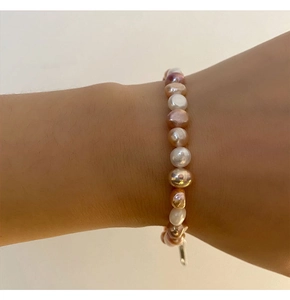Gros plan d'un bracelet en perles de culture baroques multicolores sur poignet à l'éclat vif