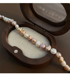 Détail de perles de culture baroques multicolores sur un élégant coffret à bijoux en bois