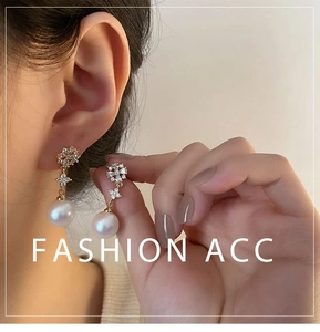Detail of floral stud earrings with sparkling crystals and a large hanging white pearl
