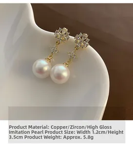 Detail of copper pearl drop earrings with zircon floral studs and star chains