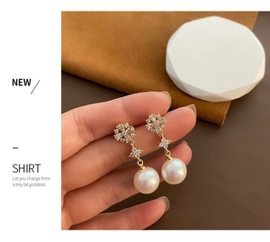 Detail of elegant gold pearl drop earrings with sparkling diamond floral stud accents