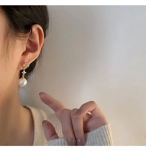 Detail of elegant pearl drop earring with zircon flower top worn by a model