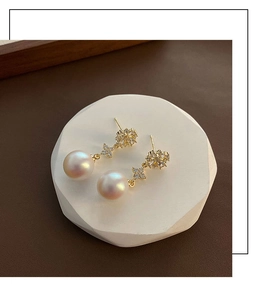 Detail of elegant gold-plated pearl earrings featuring sparkling zirconia snowflake accents