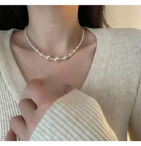 Detail of layered titanium steel necklace featuring radiant white gradient faux pearls