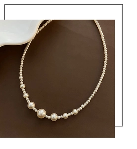Macro shot of a cream white pearl necklace with gradient sizing on a dark background