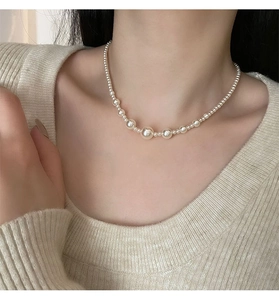 Detail of gradient pearl necklace with high-luster beads on a model's neck