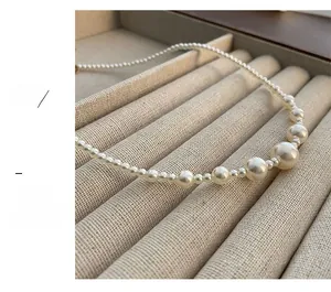Macro view of white pearl necklace with gradient bead sizing and lobster clasp on beige linen