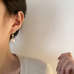Elegant gold drop earrings featuring a flower motif, star link, and white round pearls
