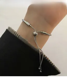 Adjustable silver snake chain bracelet featuring a sliding bead clasp on a model wrist