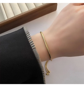 Close-up of a minimalist adjustable gold snake chain bracelet worn on a female wrist
