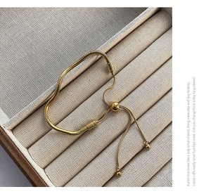 Detail of adjustable golden snake chain bracelet with sliding bead and metallic finish