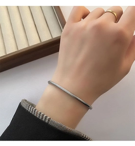 Close-up of a silver snake chain bracelet with textured metal links on a model's wrist
