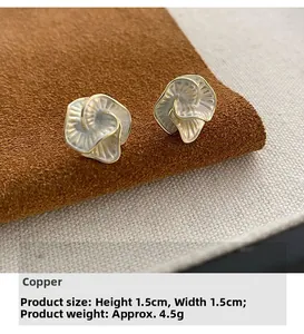 Macro detail of camellia stud earrings with gold edges and white pearlescent petals