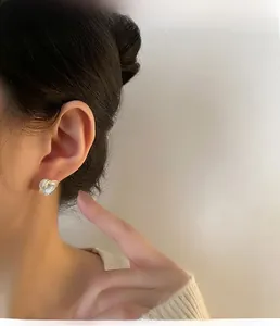 Close-up of elegant camellia flower stud earrings with pearlescent petals on model