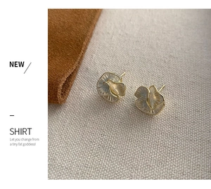 Detailed view of camellia flower studs with golden metal petals and pearly texture finish