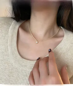 Detail of beaded gold chain necklace with a round mother of pearl pendant on a model