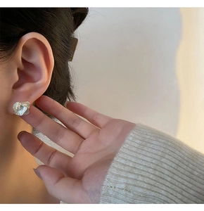 Close-up of elegant white camellia floral earring worn by a woman for scale