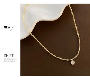 Macro view of French style yellow bead necklace with gold framed white shell pendant