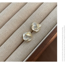 Close-up of elegant camellia stud earrings with pearlescent petals and golden edges