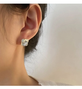 Macro detail of camellia flower earrings with gold edges and pearl-like textures