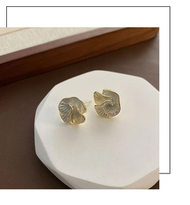 Detailed macro shot of floral petal earrings with gold trim and grey pearl finish