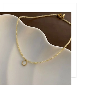 Macro shot of yellow beaded necklace with a golden round pendant on a wavy white tray