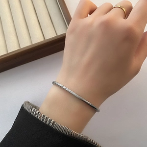 Elegant adjustable silver snake chain bracelet shown on a model's wrist with a gold ring