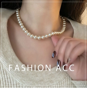 Gros plan d'un collier de perles crème élégant sur mannequin en pull beige