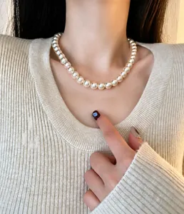 Collier ras du cou en perles élégantes porté par un mannequin en pull en maille beige