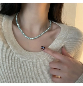Détail d'un collier de perles vert menthe élégant porté avec lumière douce