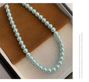 Vue détaillée d'un collier de perles bleu clair avec fermoir doré en boîte à bijoux