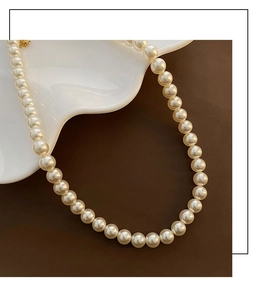 Gros plan d'un collier de perles élégant avec fermoir en métal doré sur plateau décoratif